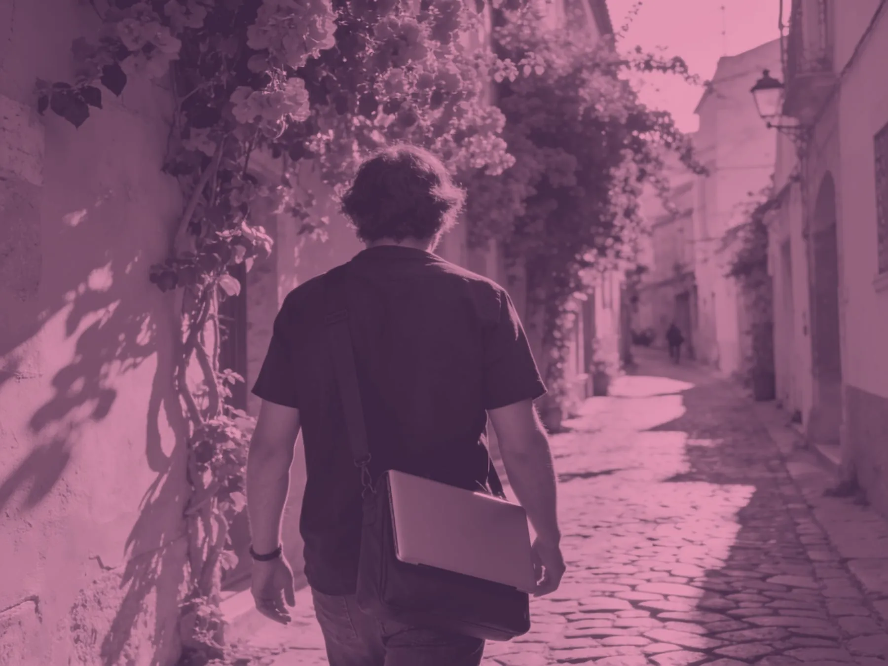 Someone walking down a sunny street with a laptop bag